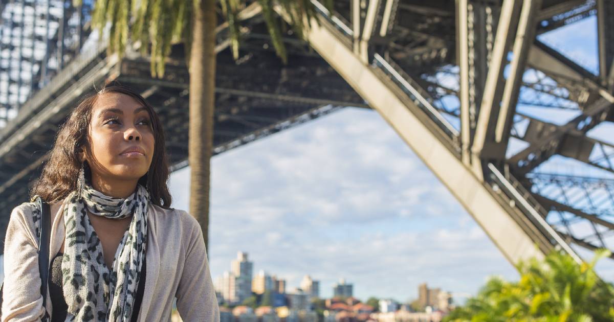 Young woman walks underneath the Sydney Harbour bridge