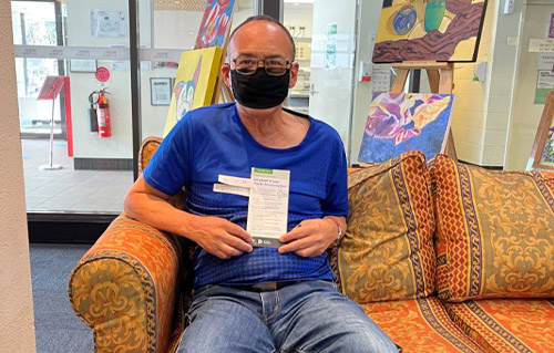 Man sitting on couch wearing a mask after receiving the COVID-19 vaccine