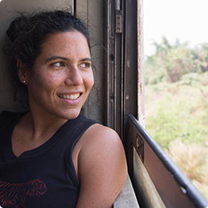A woman smiling and looking outside of a moving train