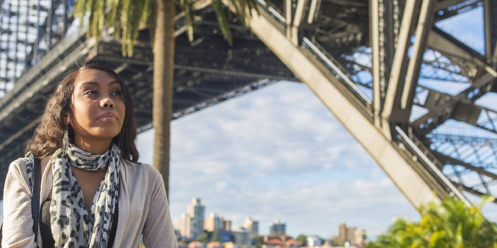 Young woman walks underneath the Sydney Harbour bridge