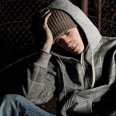 Young boy sitting against a fence