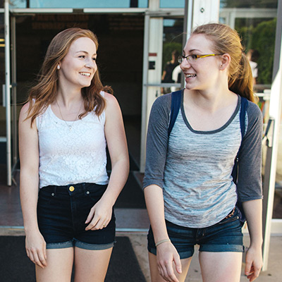 Two young girls walking down a hallway