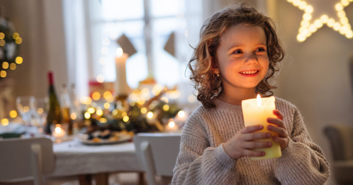 young child holds a candle at Christmas time