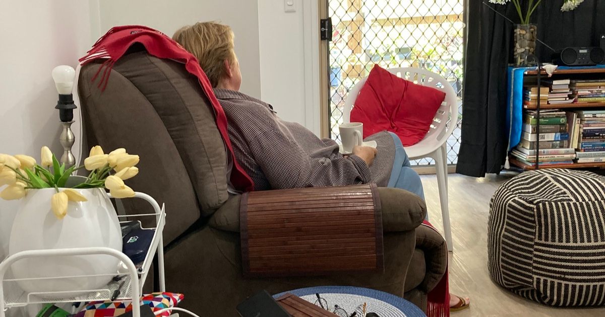 Sarah with a cup of coffee on an armchair