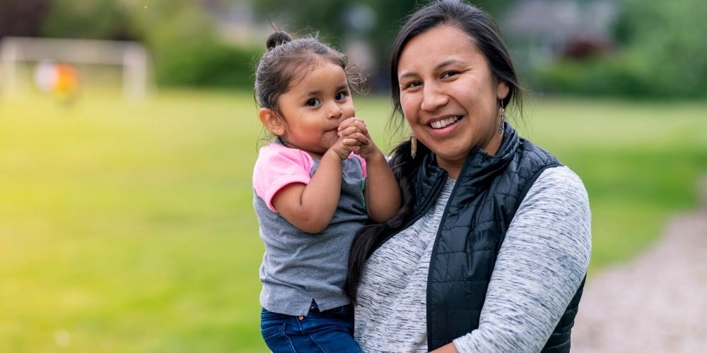 Gemma holds her daughter, Melody as they smile towards the camera