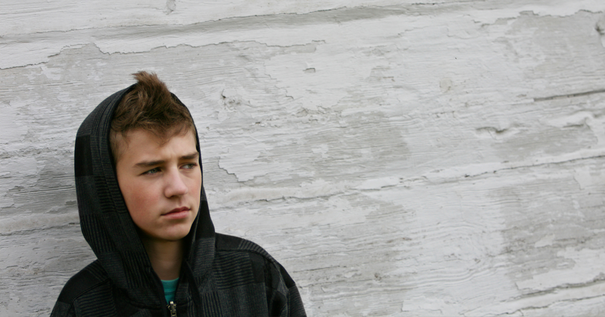 A young boy standing in the street with a hoodie