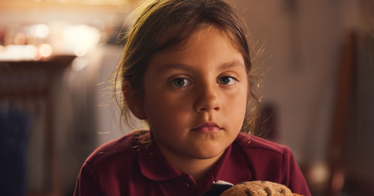 School girl looks sad into the camera in make shift home