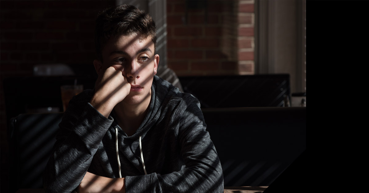 A Teenager is looking concerned in the dark