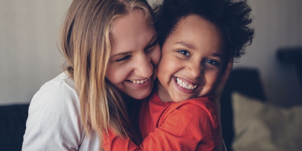 A young women is hugged by a young boy.