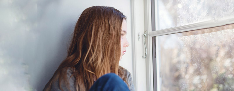 Young person looking out window