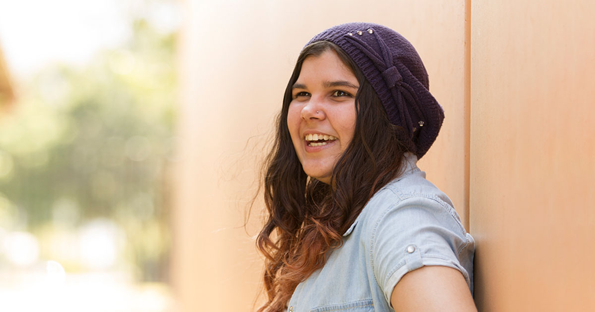 Young girl leaning on a wall smiling