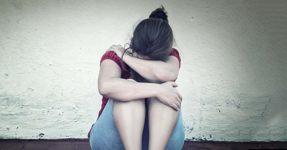 Woman afraid, huddling on the floor. One woman every nine days is killed by a current or former partner.