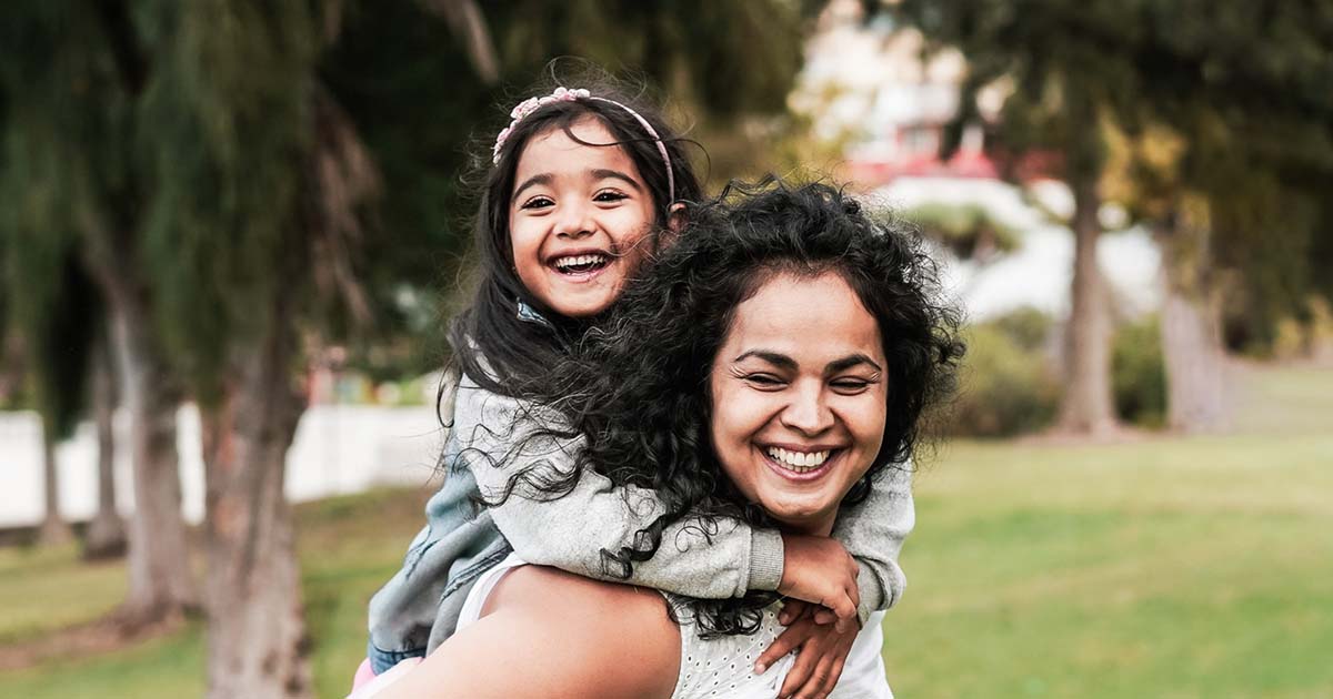 A smiling Julia carrying her daughter