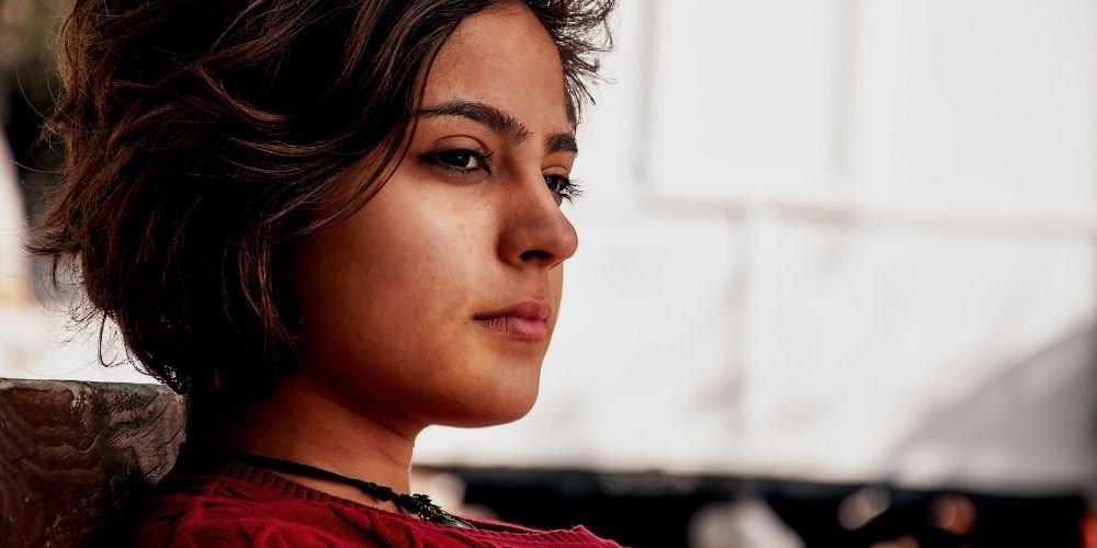 Young woman with brown hair looking away from the camera thinking