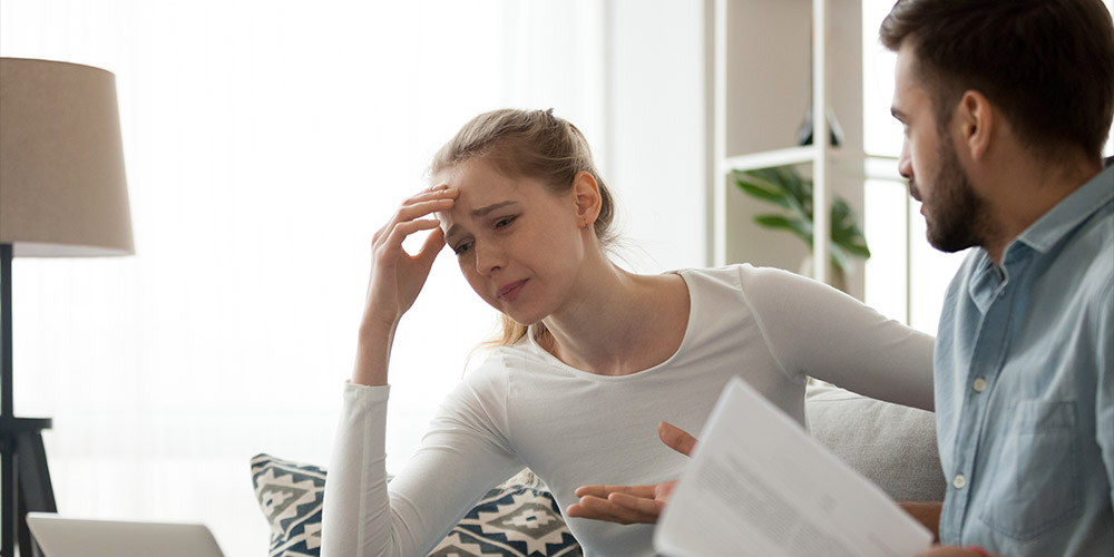 Wife looking sad with husband holding paper documents