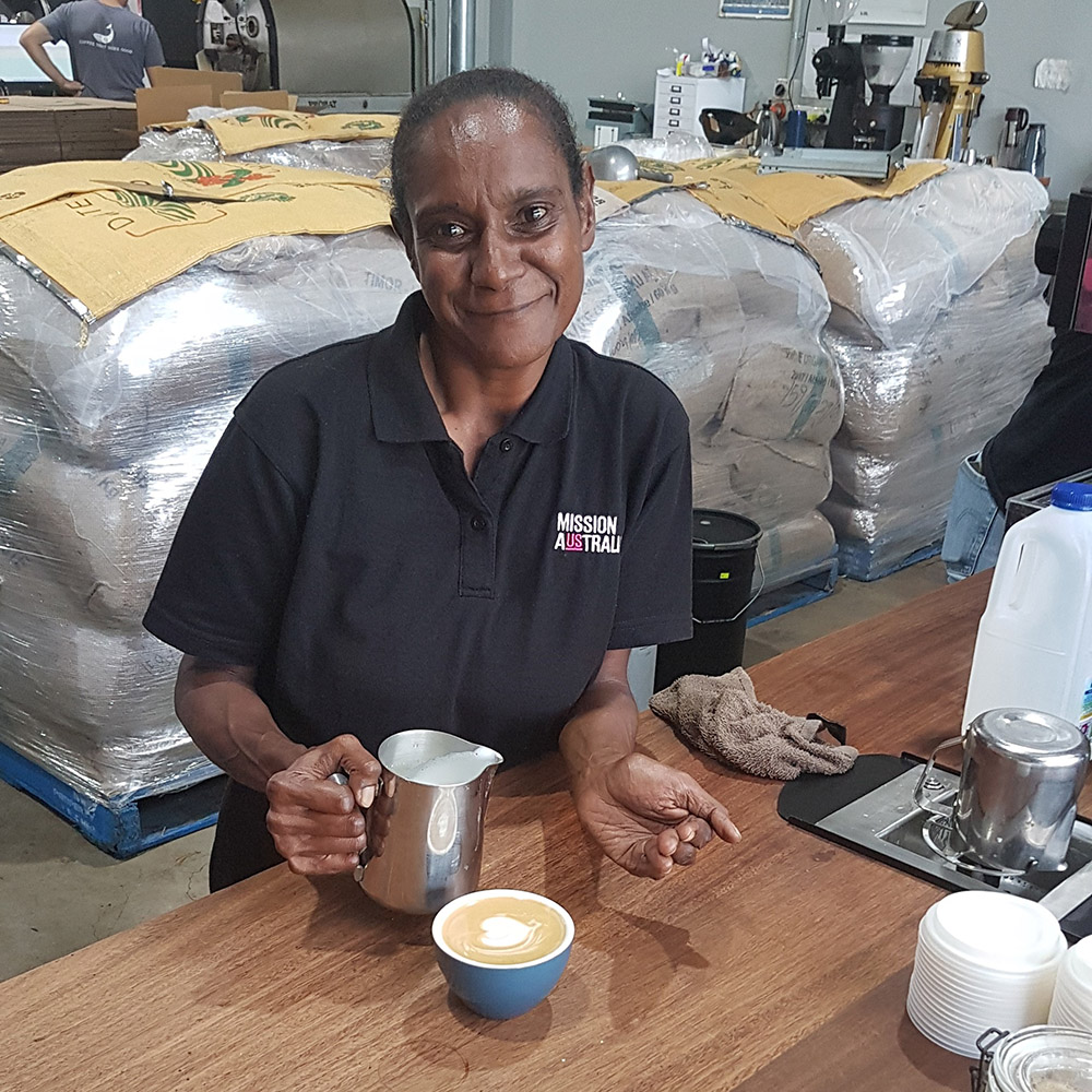 Women making a coffee and smiling toward the camera.