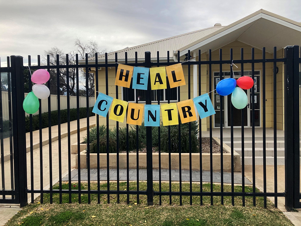 "Heal Country” sign across a gate.  