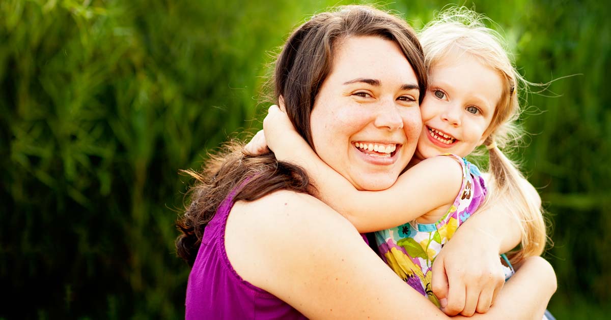 Mum and smiling young daughter hugging